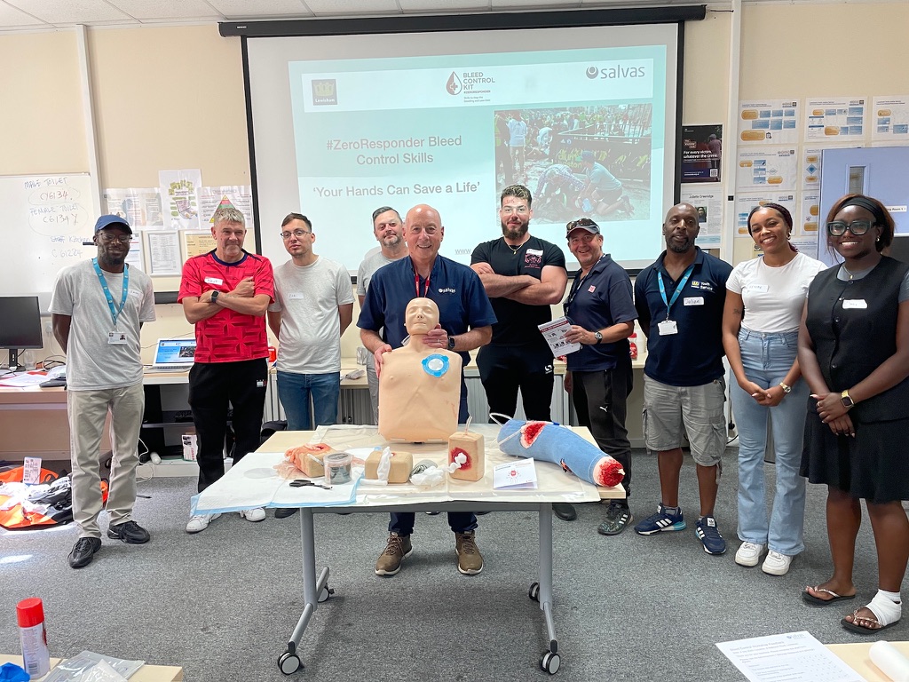 Group of Youth workers and School Staff from Millwall FC and Lewisham Council and Knights Haberdasher School standing around a table with their Bleed Control Tutor and Training manikins